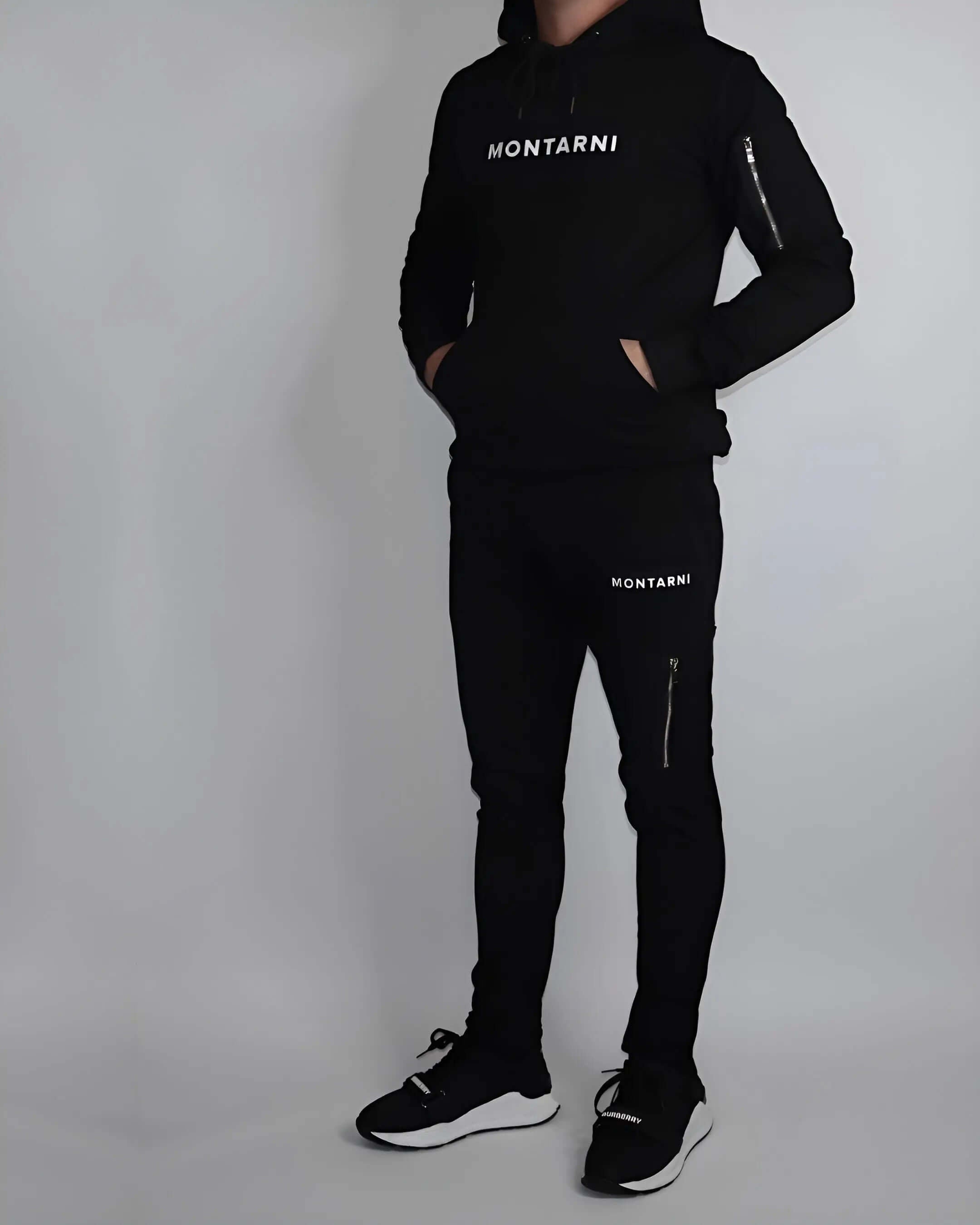 Model wearing Montarni mens tech hoodie in black featuring adjustable hood, ribbed cuffs and arm zip pocket