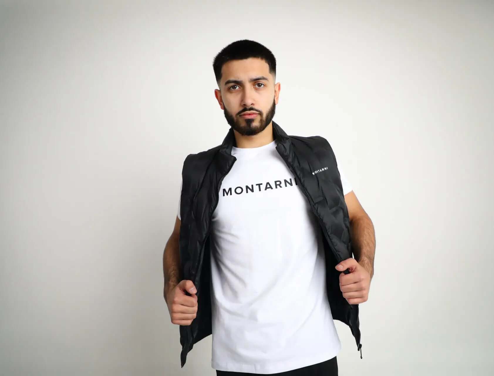 Model wearing Montarni mens black padded gilet styled over a long‑sleeve top, featuring front zip and cosy collar